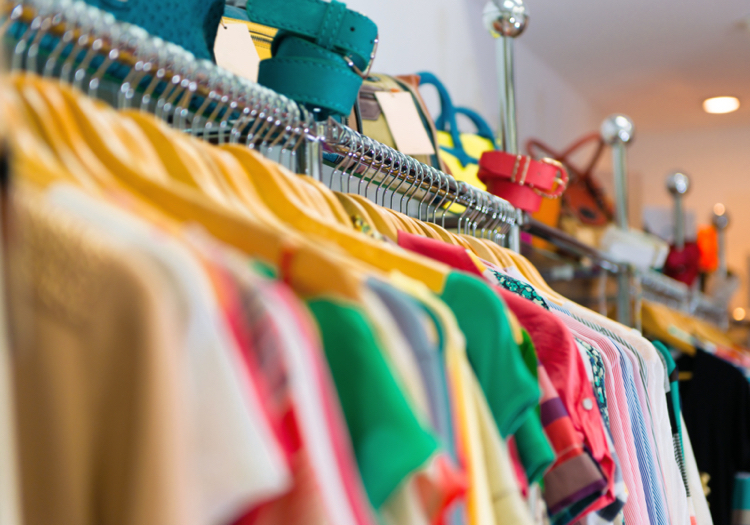 Variety of clothes hanging on rack in boutique
